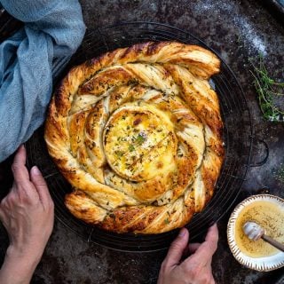Puff pastry spiral with baked camembert, honey, rosemary and thyme on a tray