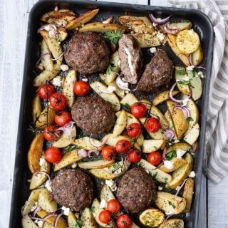 Oven tray with Greek bifteki, potato wedges and vine tomatoes