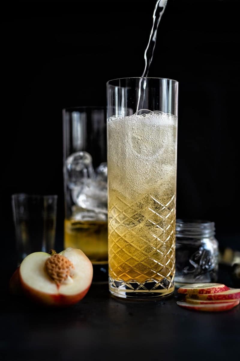 Topping a sparkling peach whisky cocktail with chilled soda water