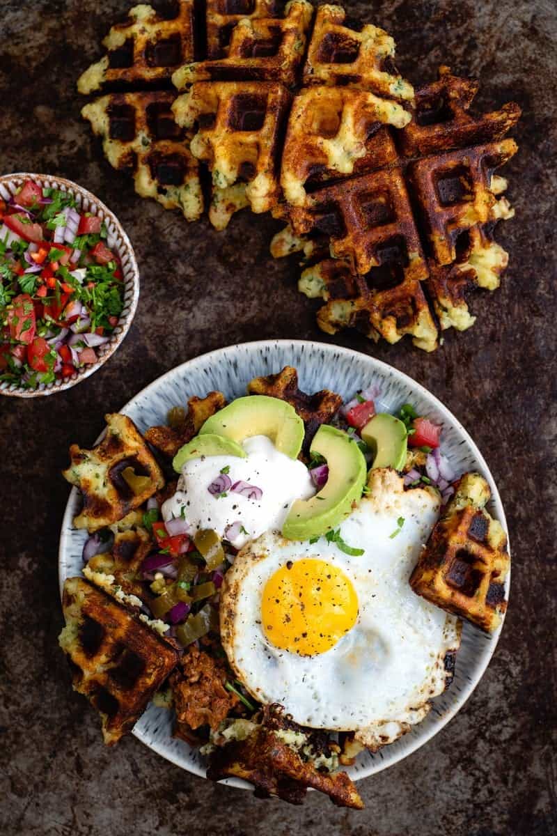 mashed potato waffles topped with egg, salsa, soured cream and avocado