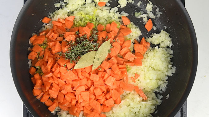Frying onions, celery, carrots and herbs in a pan