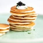 Stack of blini pancakes topped with sour cream and caviar