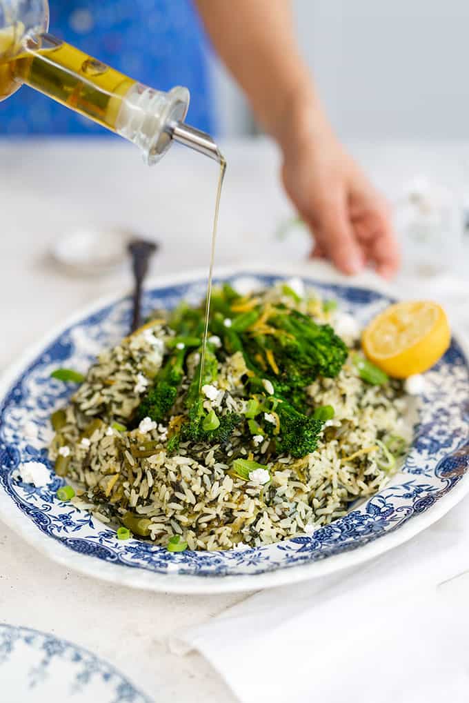 Platter of Greek spinach rice topped with broccoli spears with olive oil drizzle