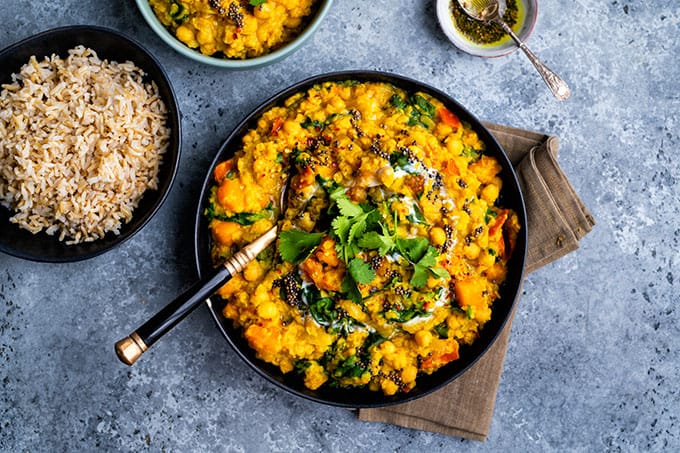 Vegan dal with red lentils, squash, chickpeas and spinach in a bowl with rice on the side