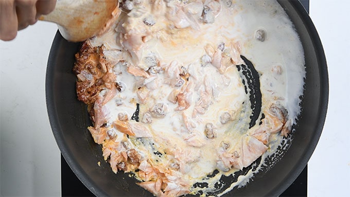 Adding cream to a pan of creamy salmon chorizo sauce