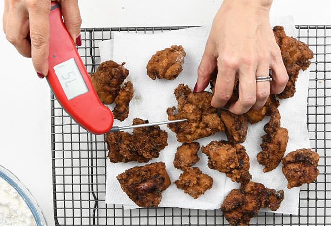 Checking internal temperature of fried chicken with a digital thermometer