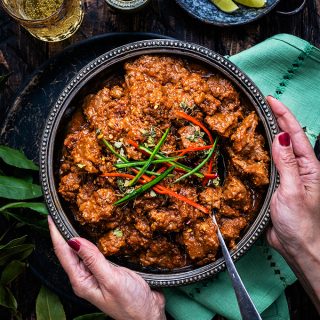 Overhead image of large bowl of lamb curry on a rustic wood table