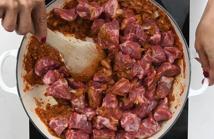 Coating lamb in bhuna spices in a shallow casserole pan