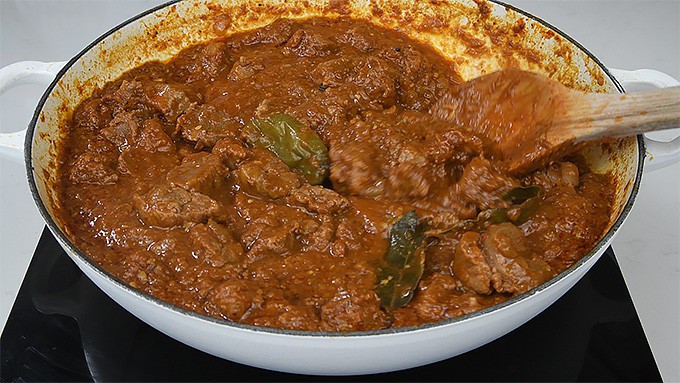 Close up on lamb curry cooking in a shallow pan