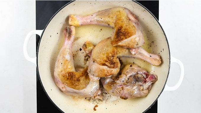 Chicken legs browning in a shallow casserole dish