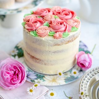 Birthday cake decorated with pink buttercream roses on a floral plate