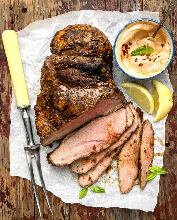 Grilled boneless leg of lamb partly sliced on a wooden board