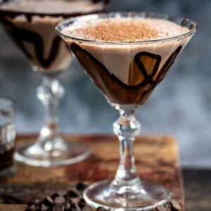 Two martini glasses decorated with chocolate syrup and filled with chocolate cocktail