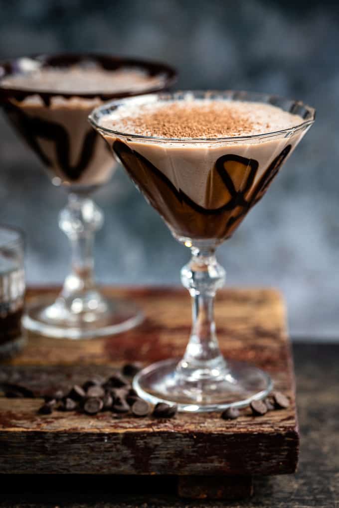 Two martini glasses decorated with chocolate syrup and filled with chocolate cocktail