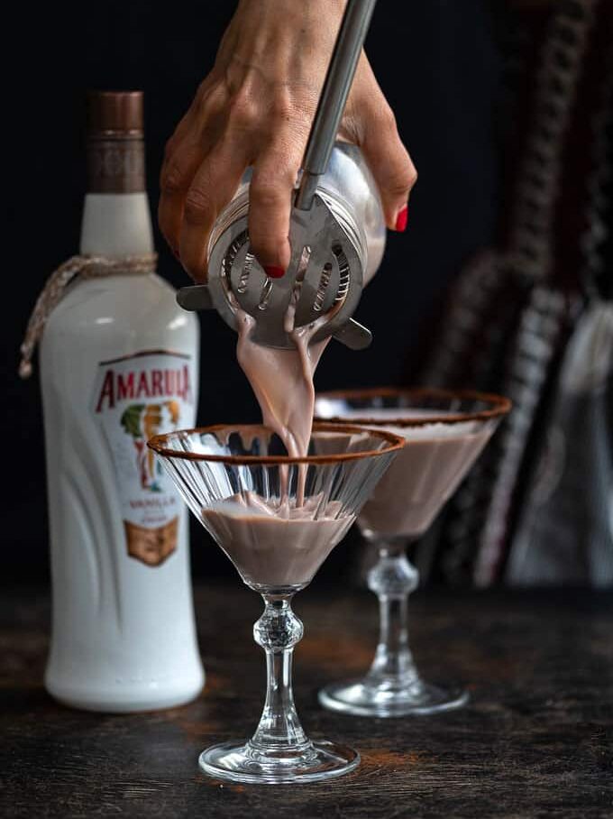 Pouring chocolate martini into cocktail glass frosted with cocoa powder