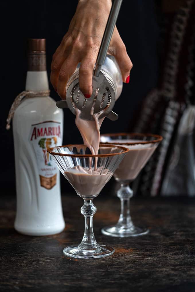 Pouring chocolate martini into cocktail glass frosted with cocoa powder