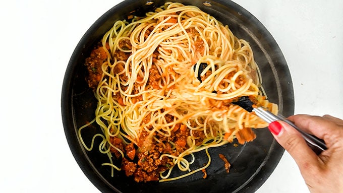 tossing spaghetti with bolognese sauce