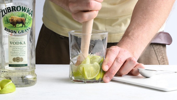Muddling limes in a rocks glass for a vodka cocktail