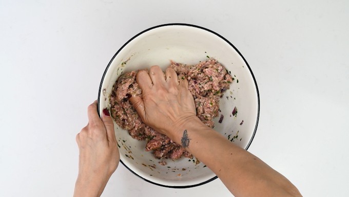 Mixing meat mixture by hand in a large bowl