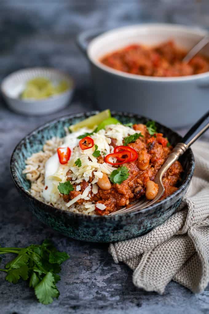 Bowl of Chilli Con Carne with grated cheese and sour cream served over rice