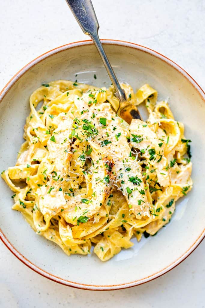 Bowl of Chicken Alfredo garnished with chopped parsley