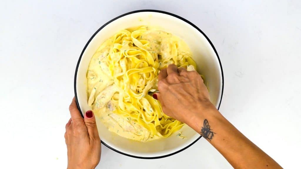 stirring cooked pasta to creamy sauce