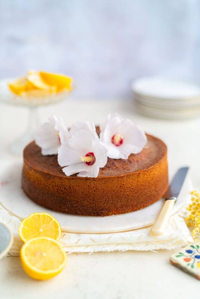 Lemon Drizzle Cake on a marble plate decorated with fresh flowers