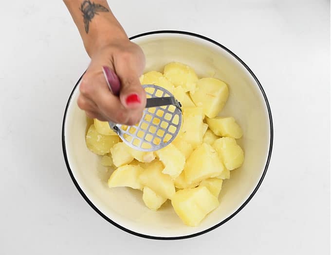 mashing potatoes in a bowl
