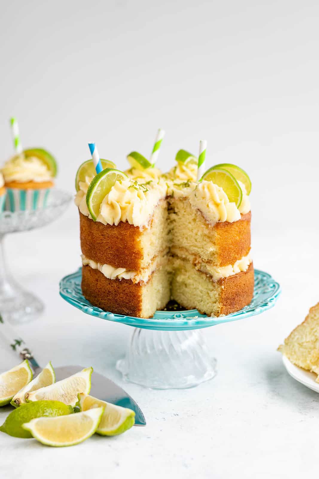 Gin and Tonic Cake on a cake stand decorated with lime wedges