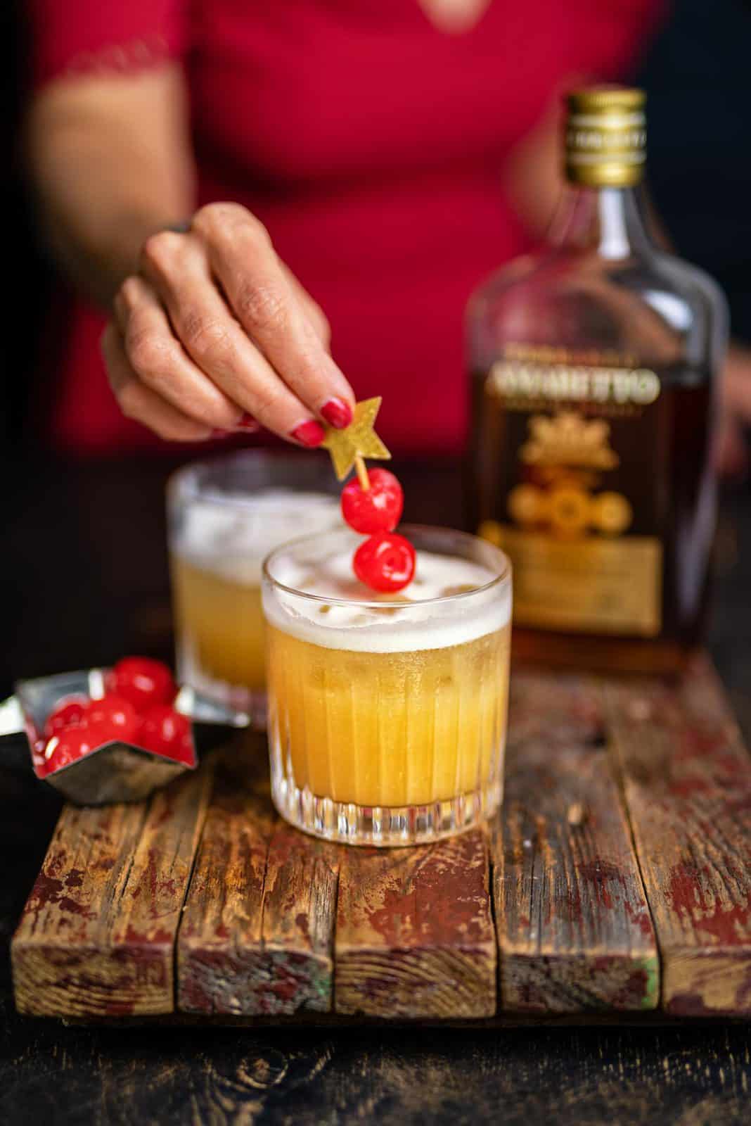 Amaretto sour in a rocks glass with cherries added