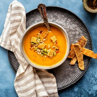 Bowl of Butternut Squash Soup garnished with seeds and croutons