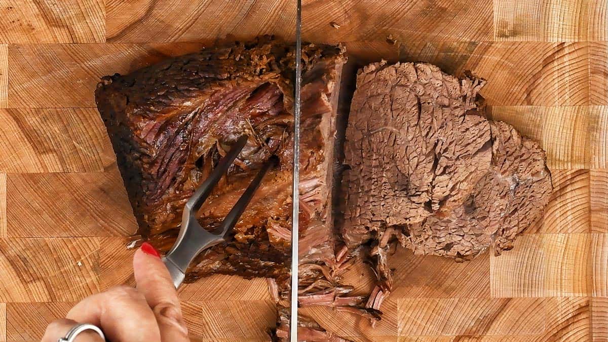 Slicing topside of beef on a wooden board