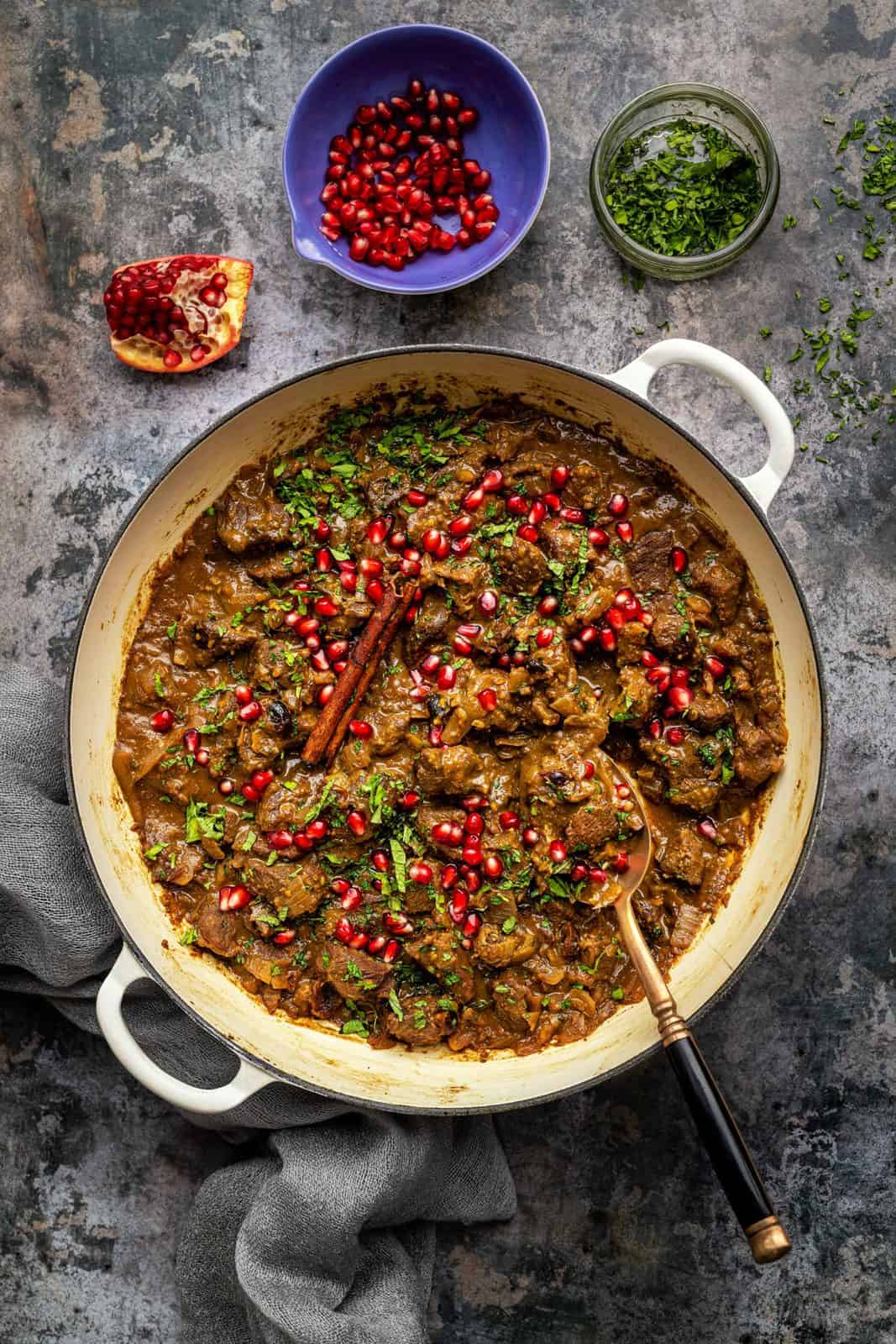 Persian Lamb stew in a shallow casserole dish garnished with pomegranate seeds and herbs