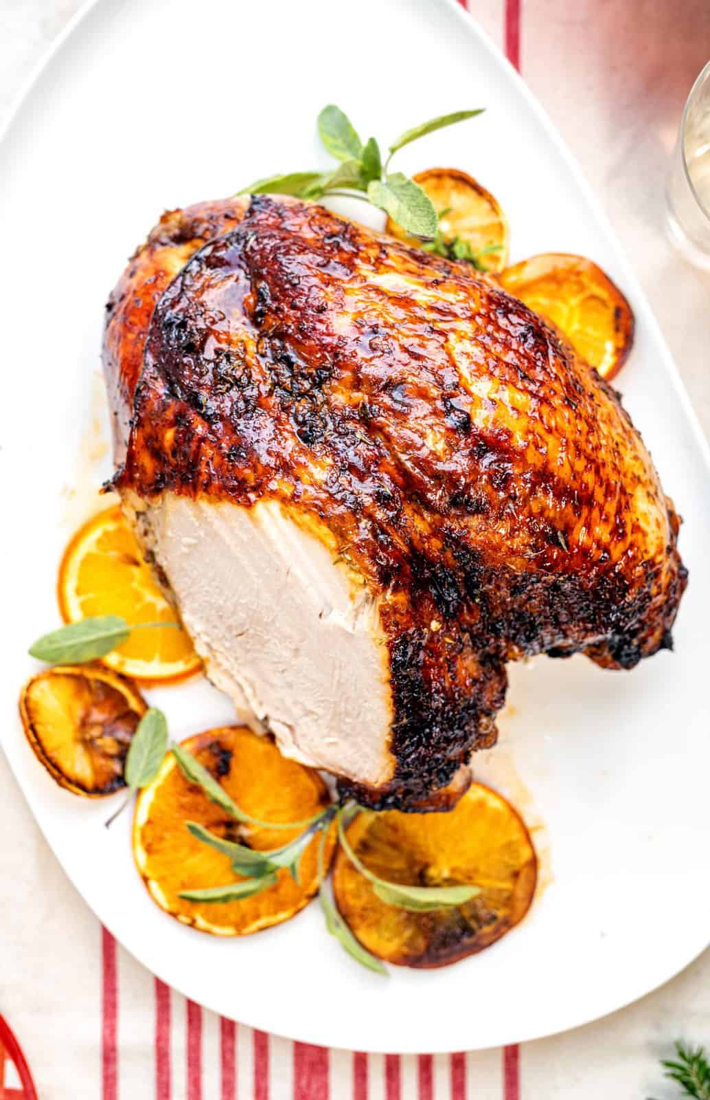 Easy roast turkey crown on a white platter with slice taken out