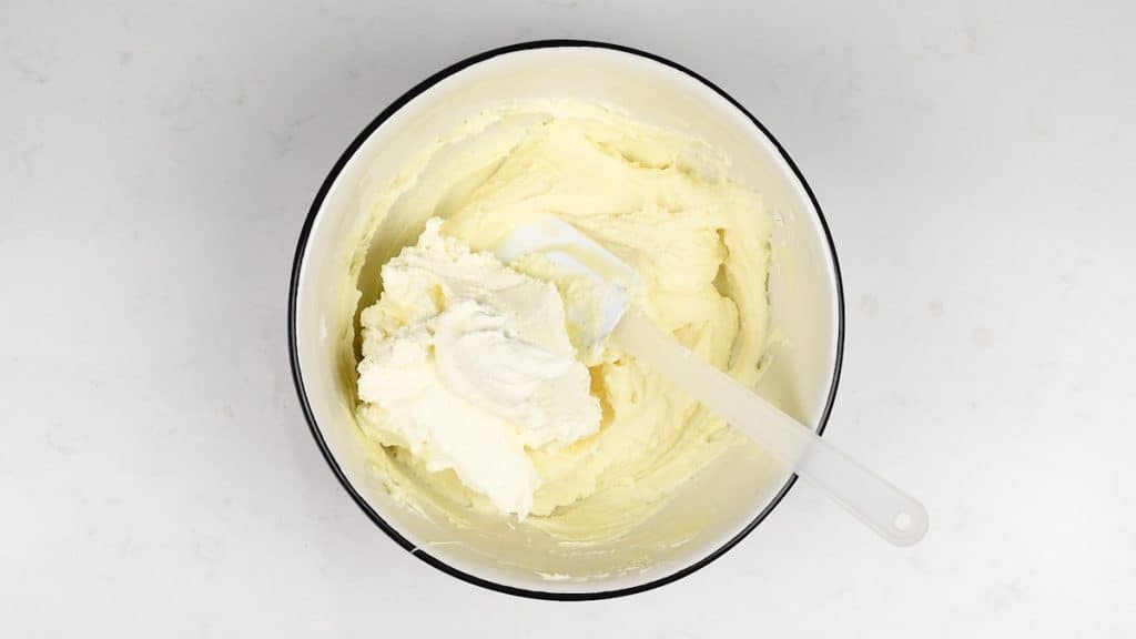 Folding whipped cream into cheesecake filling in a bowl