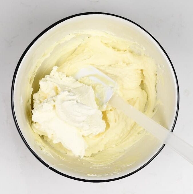 Folding whipped cream into cheesecake filling in a bowl