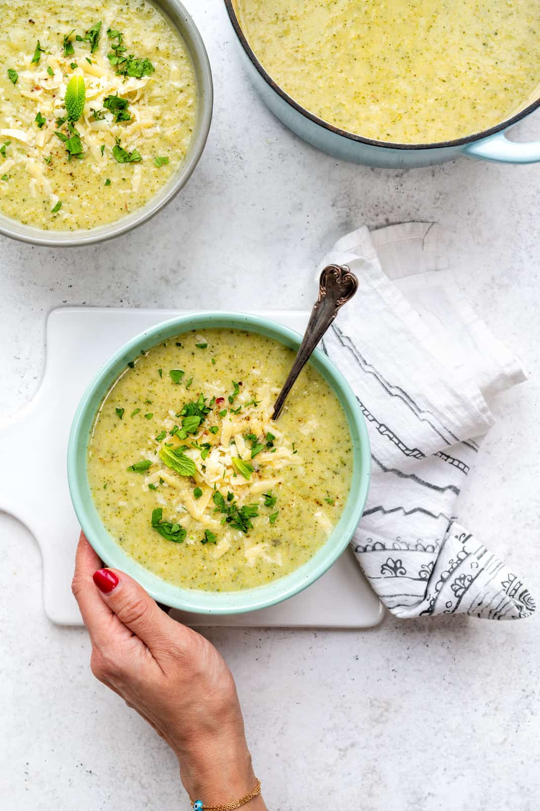 Bowl of creamy broccoli soup with grated cheddar and herb garnish