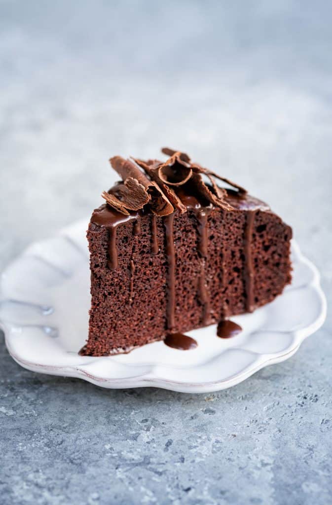 Slice of healthy flourless chocolate cake with a drizzle of chocolate and chocolate curls