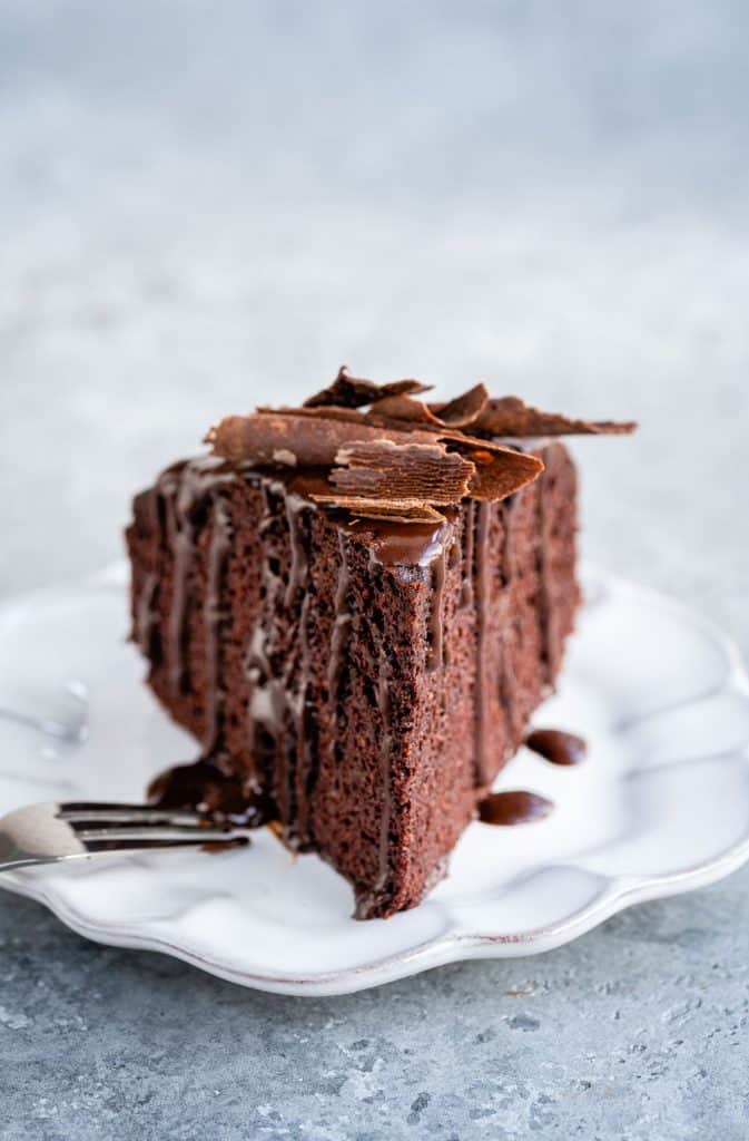 Close up on a slice of moist chocolate cake with chocolate syrup and chocolate curls