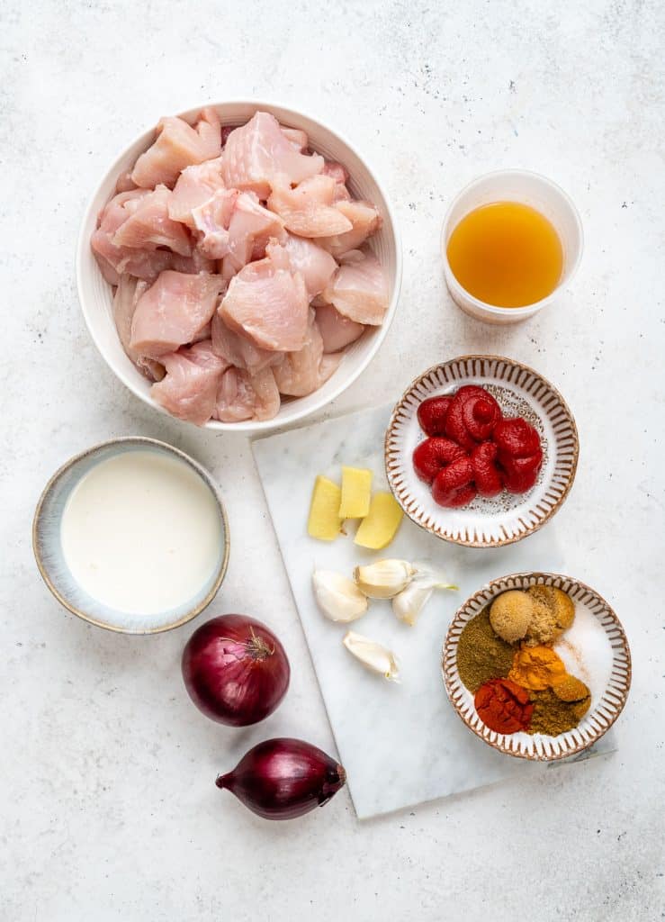Ingredients for slow cooker chicken curry laid out on a white background