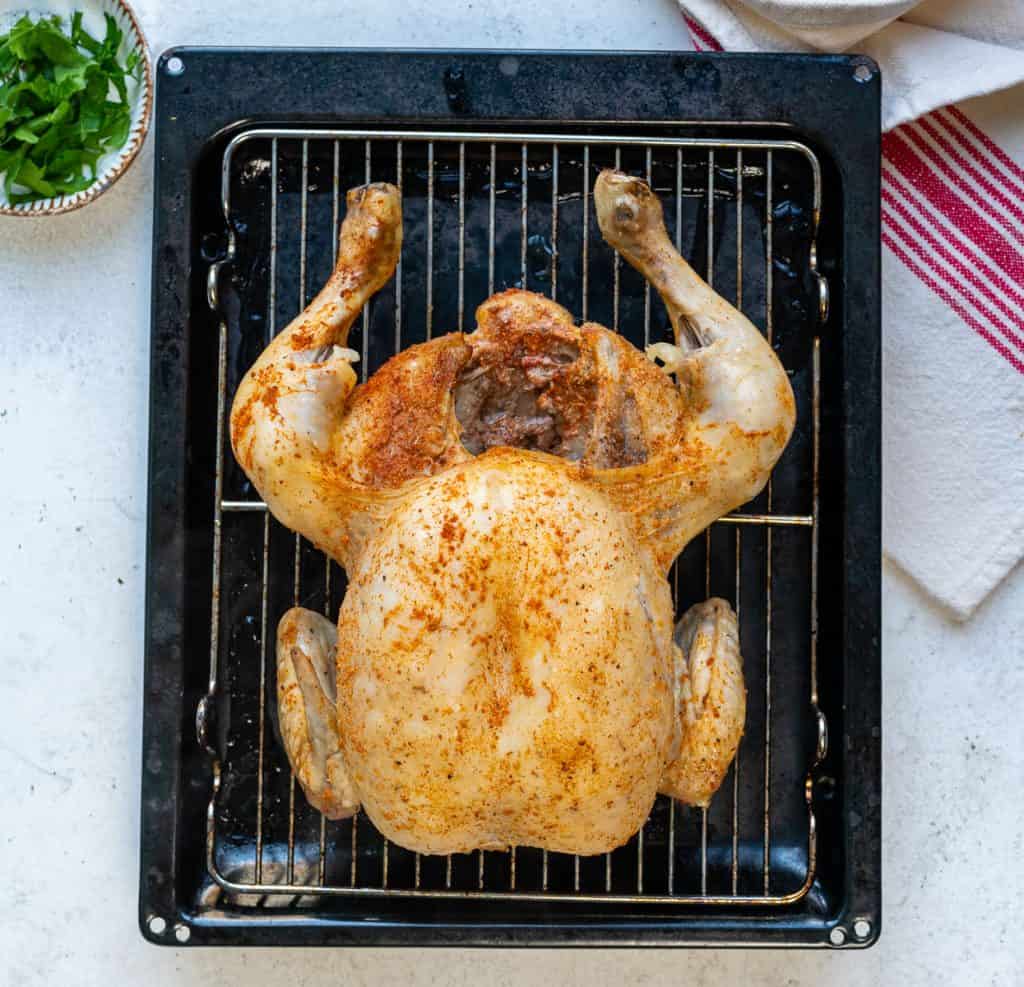Whole cooked chicken in a roasting pan