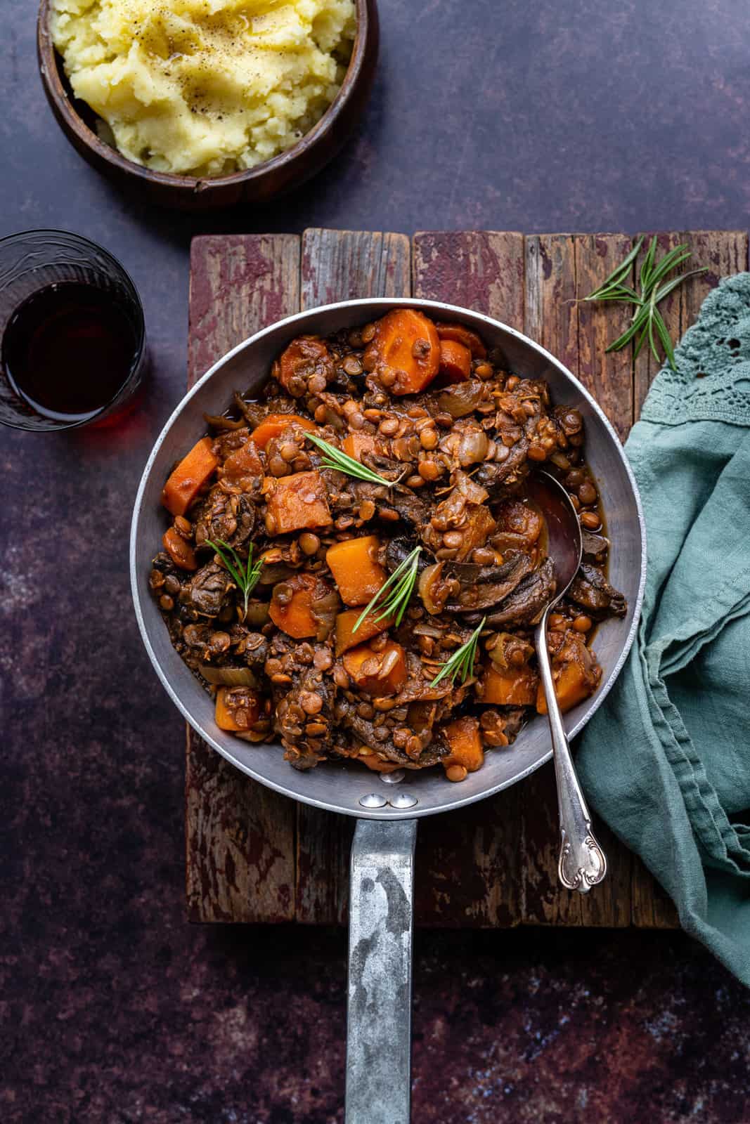 Vegan stew garnished with rosemary in a small pan