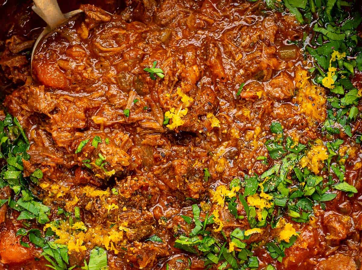Close up on beef ragu sauce garnished with parsley and lemon zest