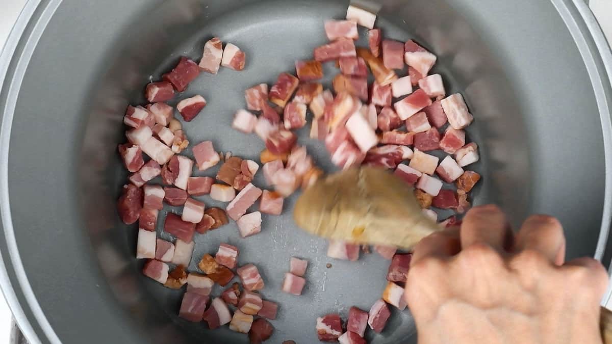 Pan frying pancetta cubes in a pot