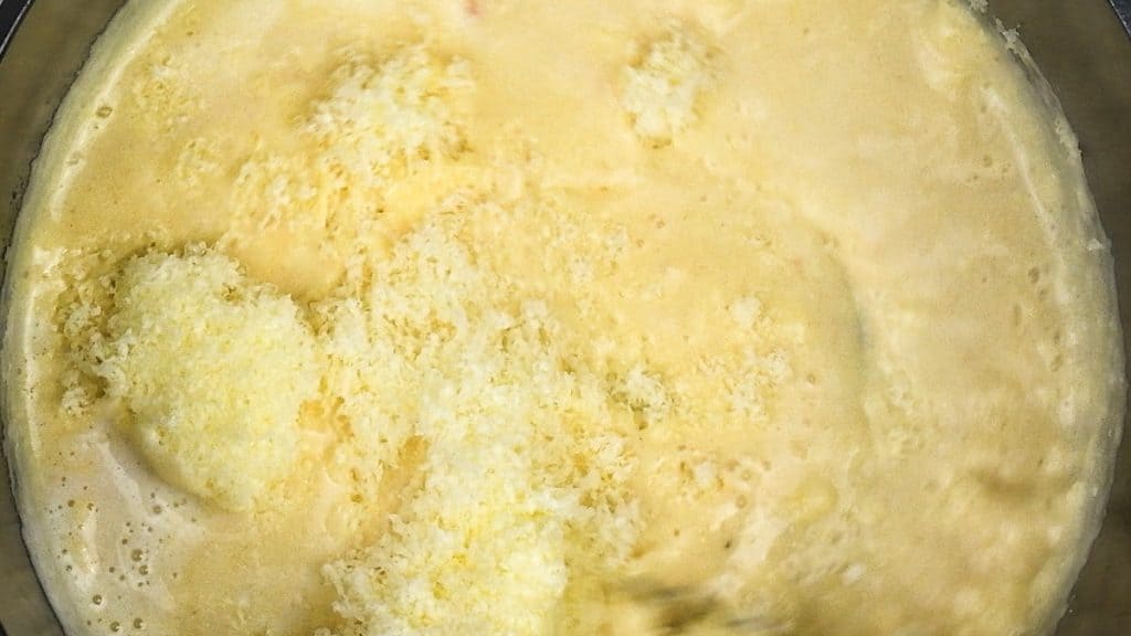 Adding grated cheddar cheese to cheese sauce
