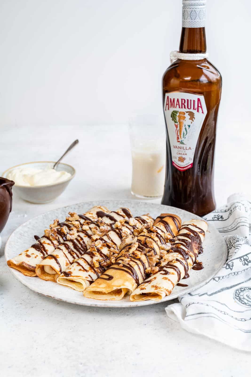 Sweet crepes filled with cream and drizzled with chocolate sauce and chopped nuts