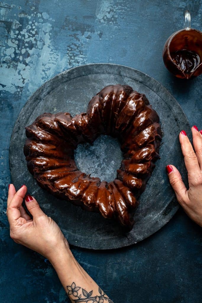 Heart shaped chocolate bundt cake with chocolate glaze on a marble board