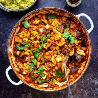 Vegetable curry in a large casserole dish with rice on the side