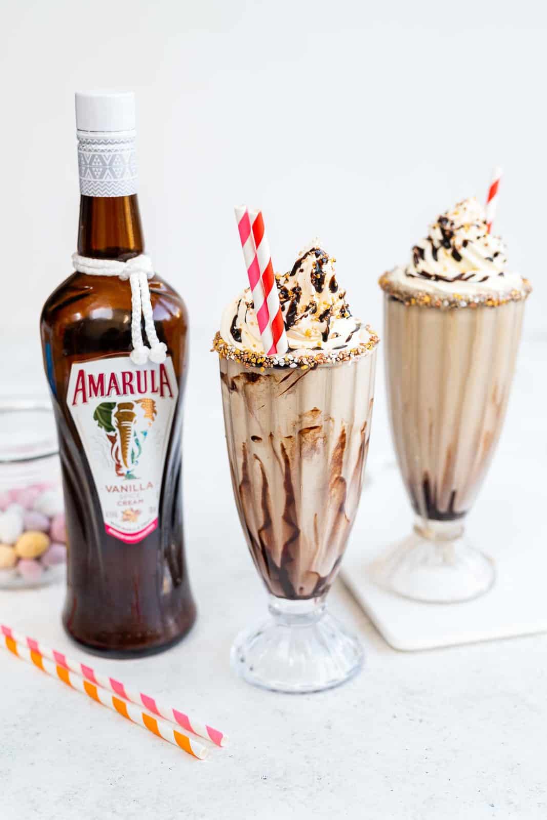Boozy Vanilla milkshakes served in sundae glasses topped with whipped cream and chocolate sauce