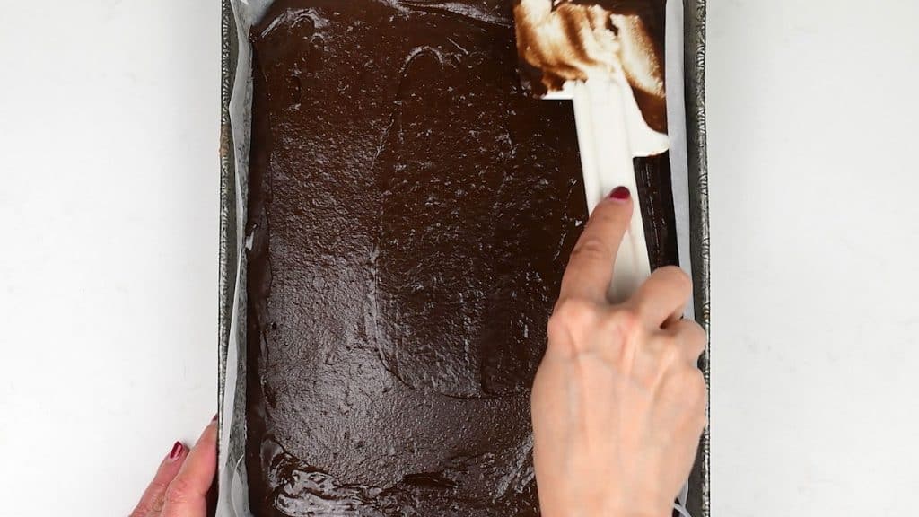 spreading chocolate cake batter in a rectangular cake tin